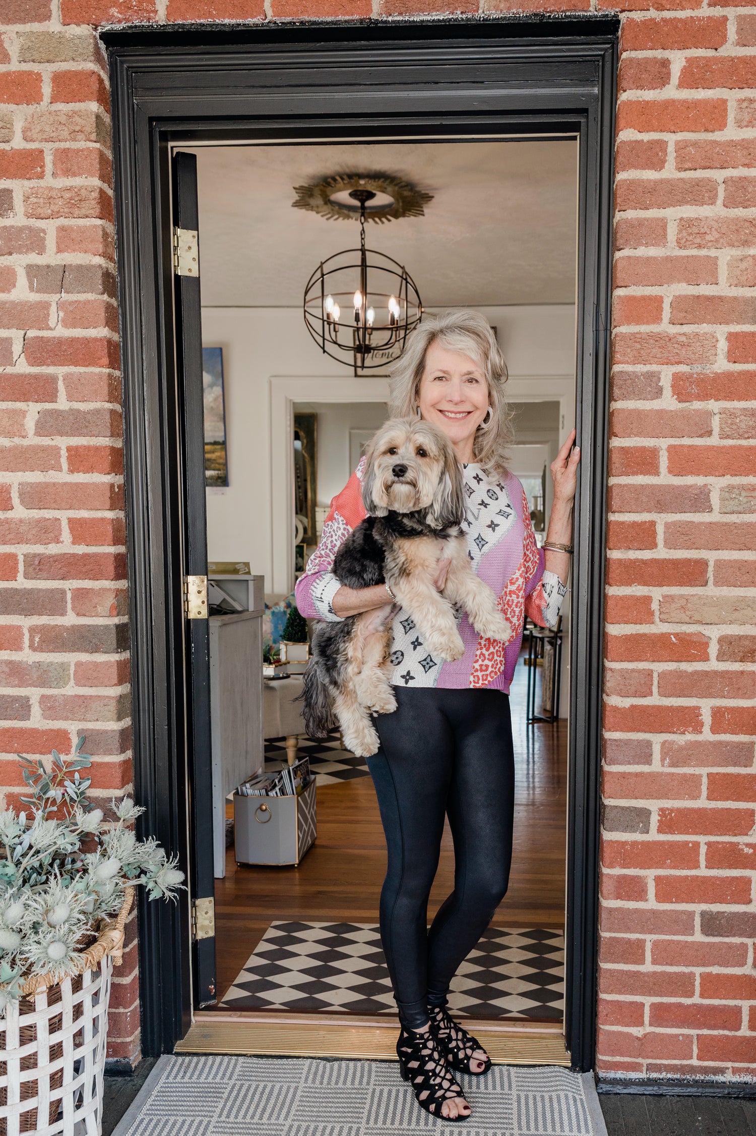 Lori Savio standing in the doorway of Home, Heart & Soul holding her dog, Enzo