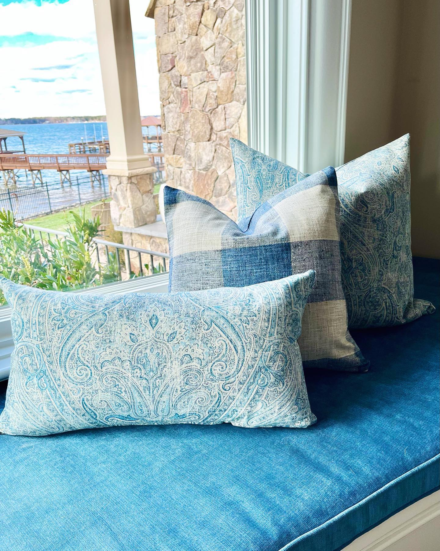Photo of blue pillows on a bench next to a window with a lakefront view
