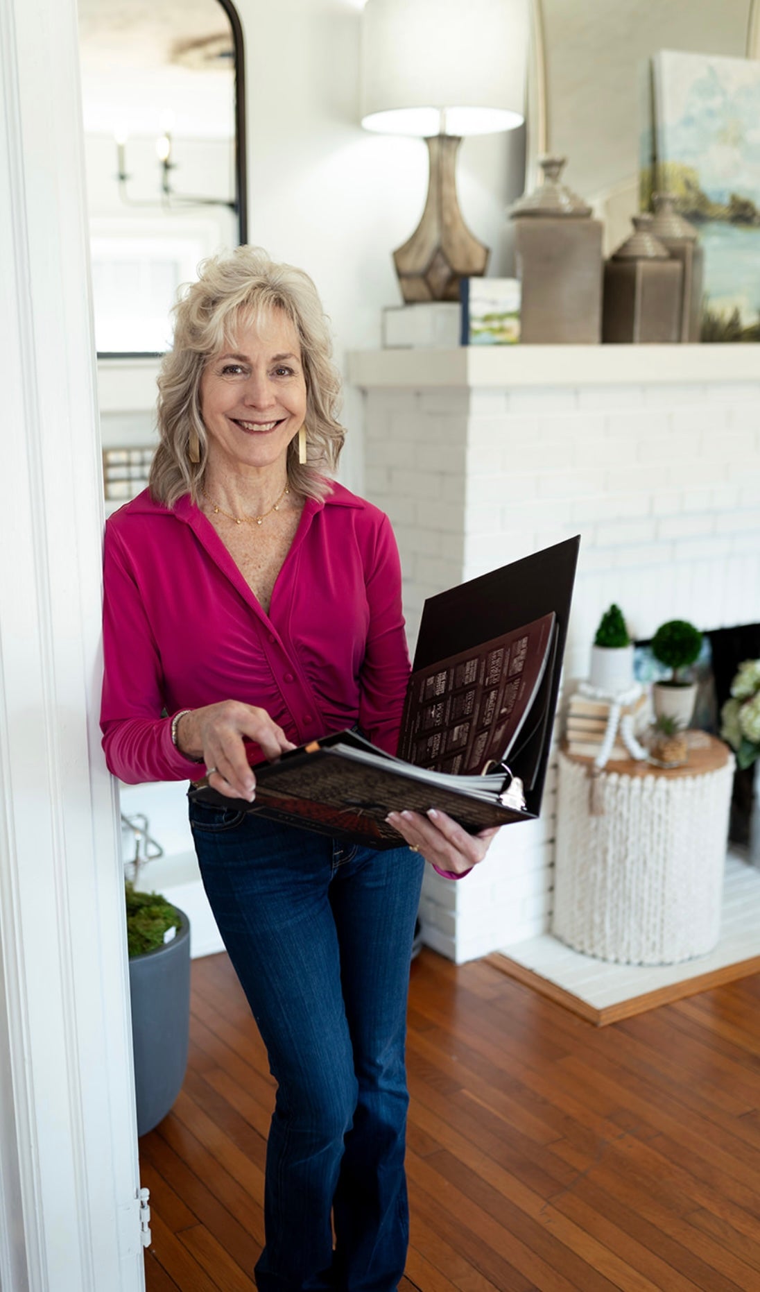 Photo of Lori Savio in her design center boutique holding an open catalogue