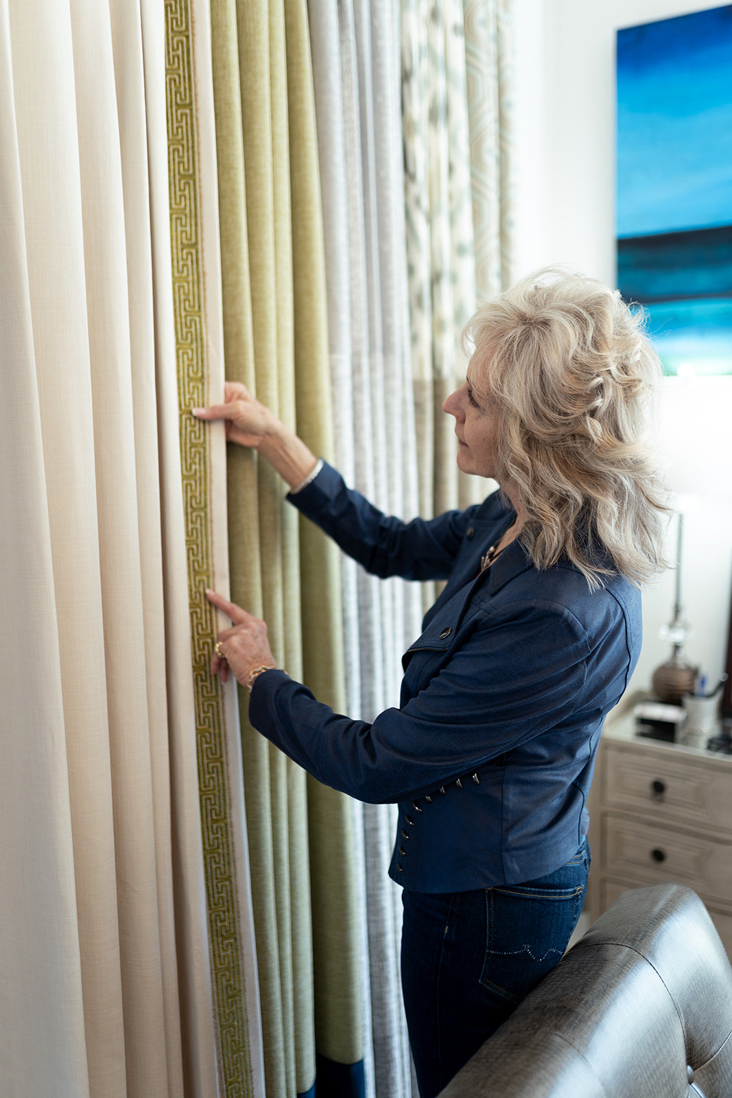 Lori Savio, Interior Designer, looking at and holding custom curtains