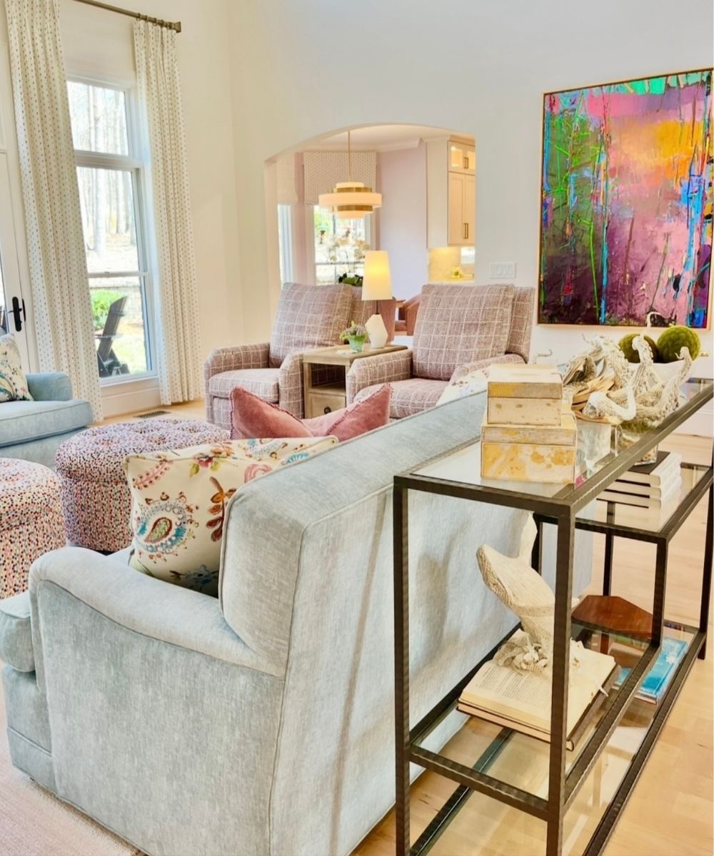 A bright living room with a gray sofa, colorful painting, and decorative items.