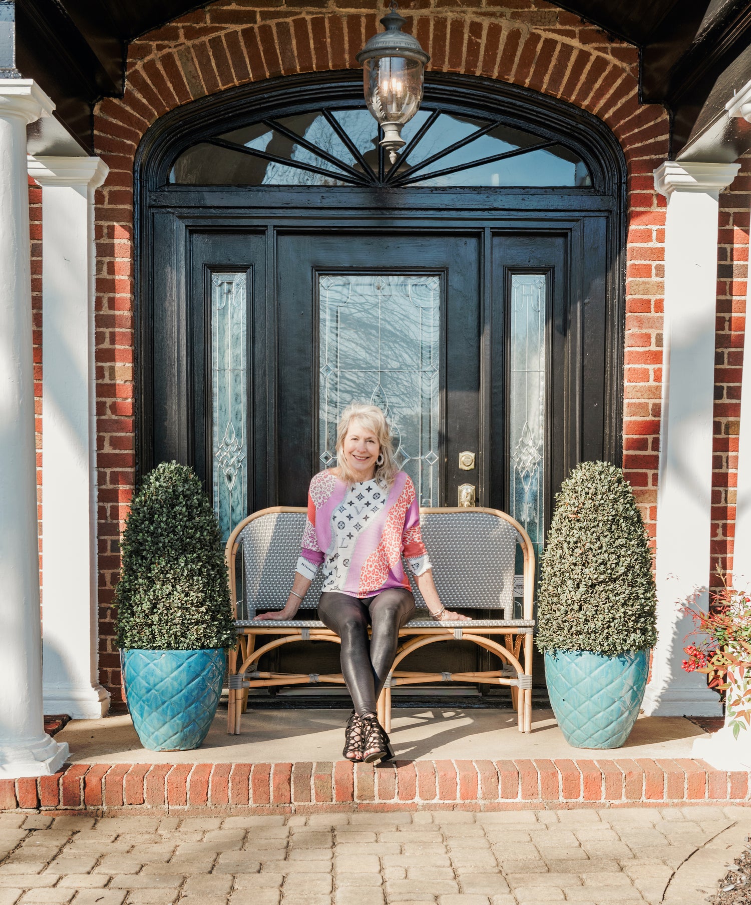 Photo of Lori Savio sitting on a bench in front of her home décor & gift shop in Cornelius, North Carolina