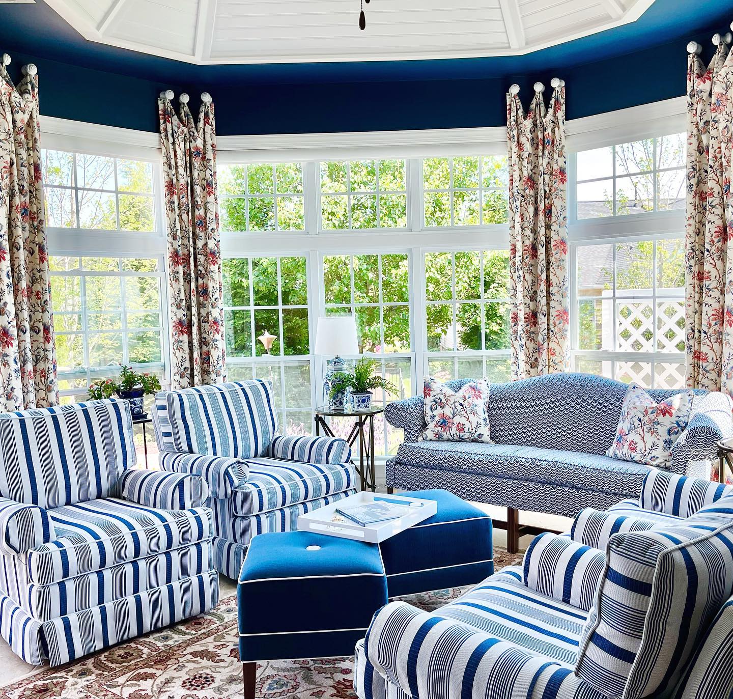 Photo of a completed sunroom seating area design project with 4 blue upholstered chairs, 2 ottomans, and a sofa