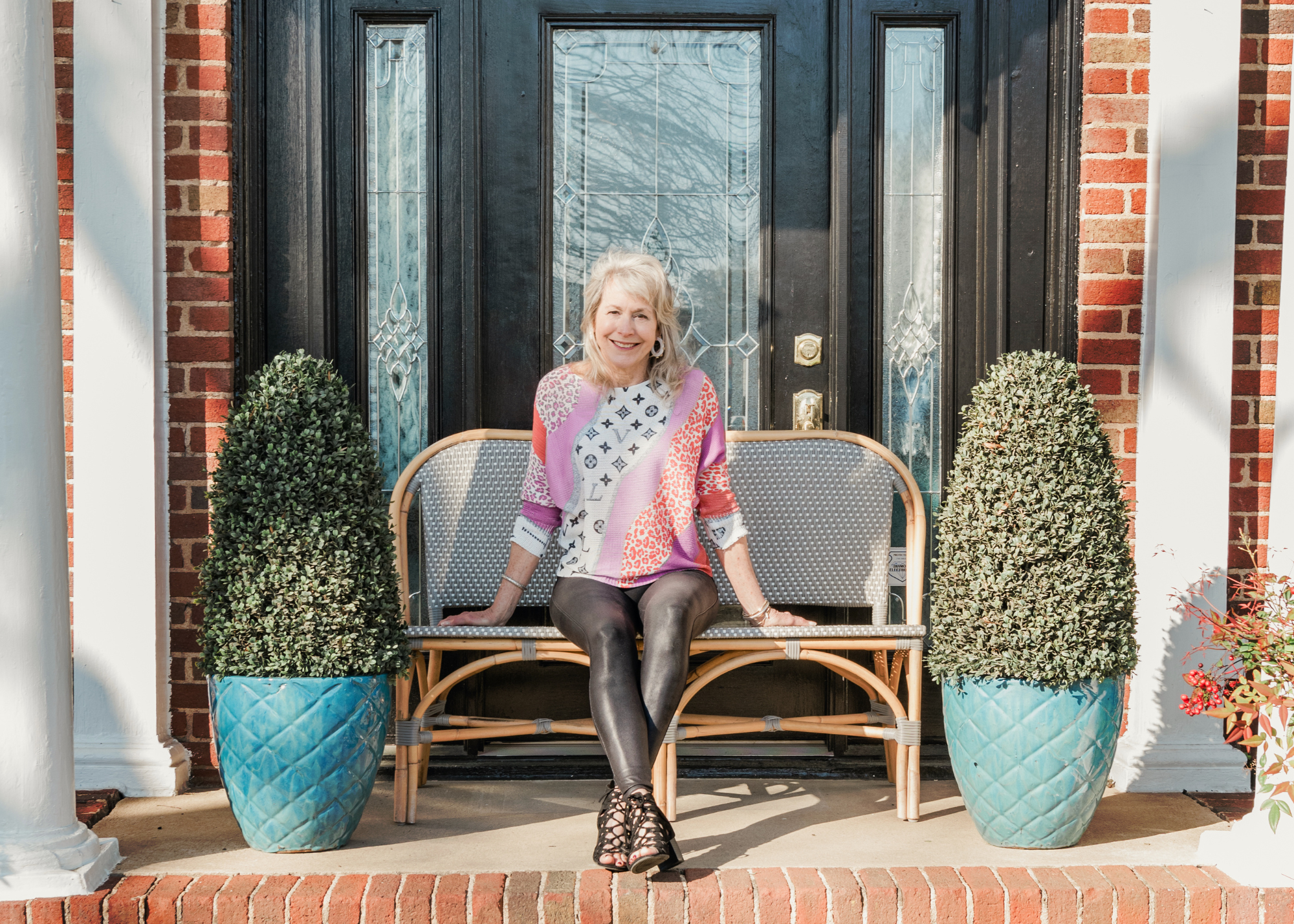 Photo of Lori Savio, Owner of Home, Heart & Soul, sitting on a bench outside of her home décor & gift shop in Cornelius, North Carolina