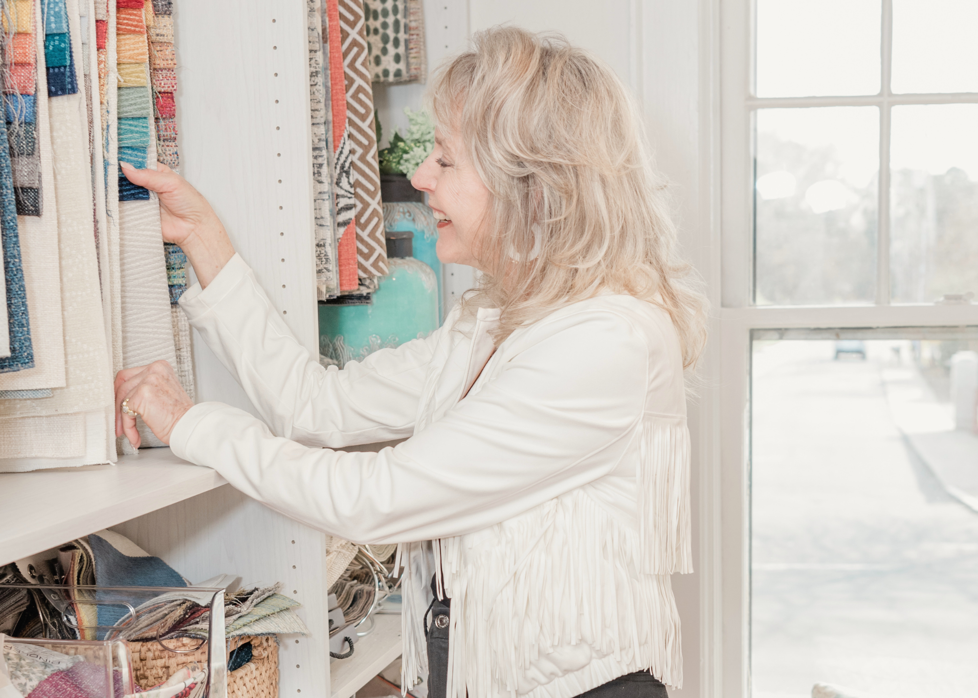 Lori Savio, Interior Designer and Owner of Home, Heart & Soul, smiling while looking through fabric samples